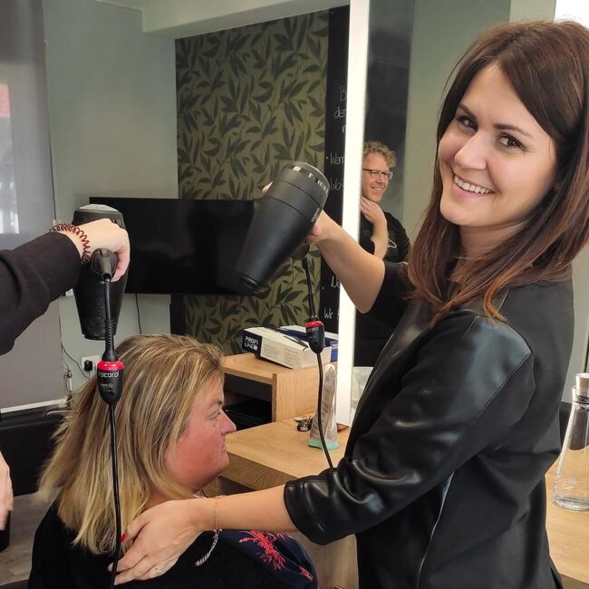 Friseurin beim Haare föhnen